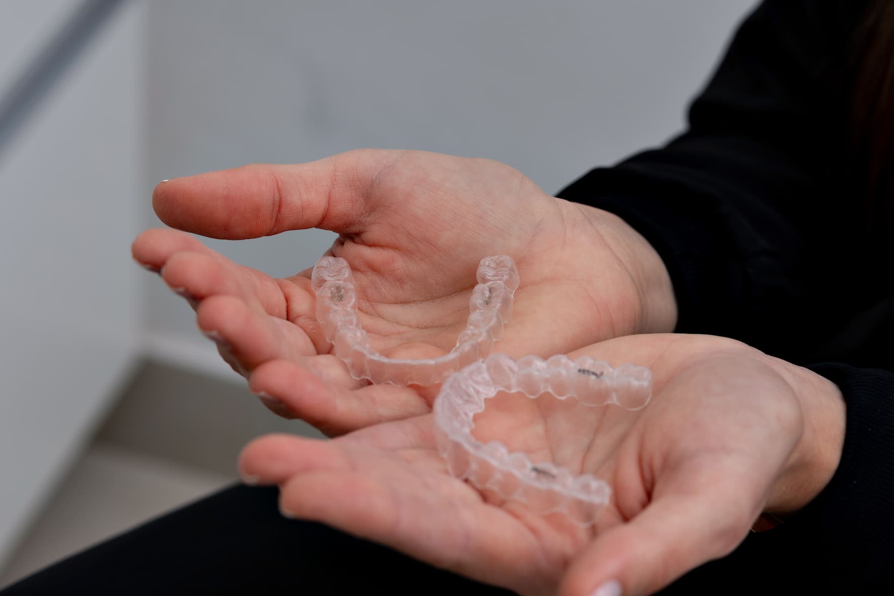 Hands holding Invisalign aligners or retainers