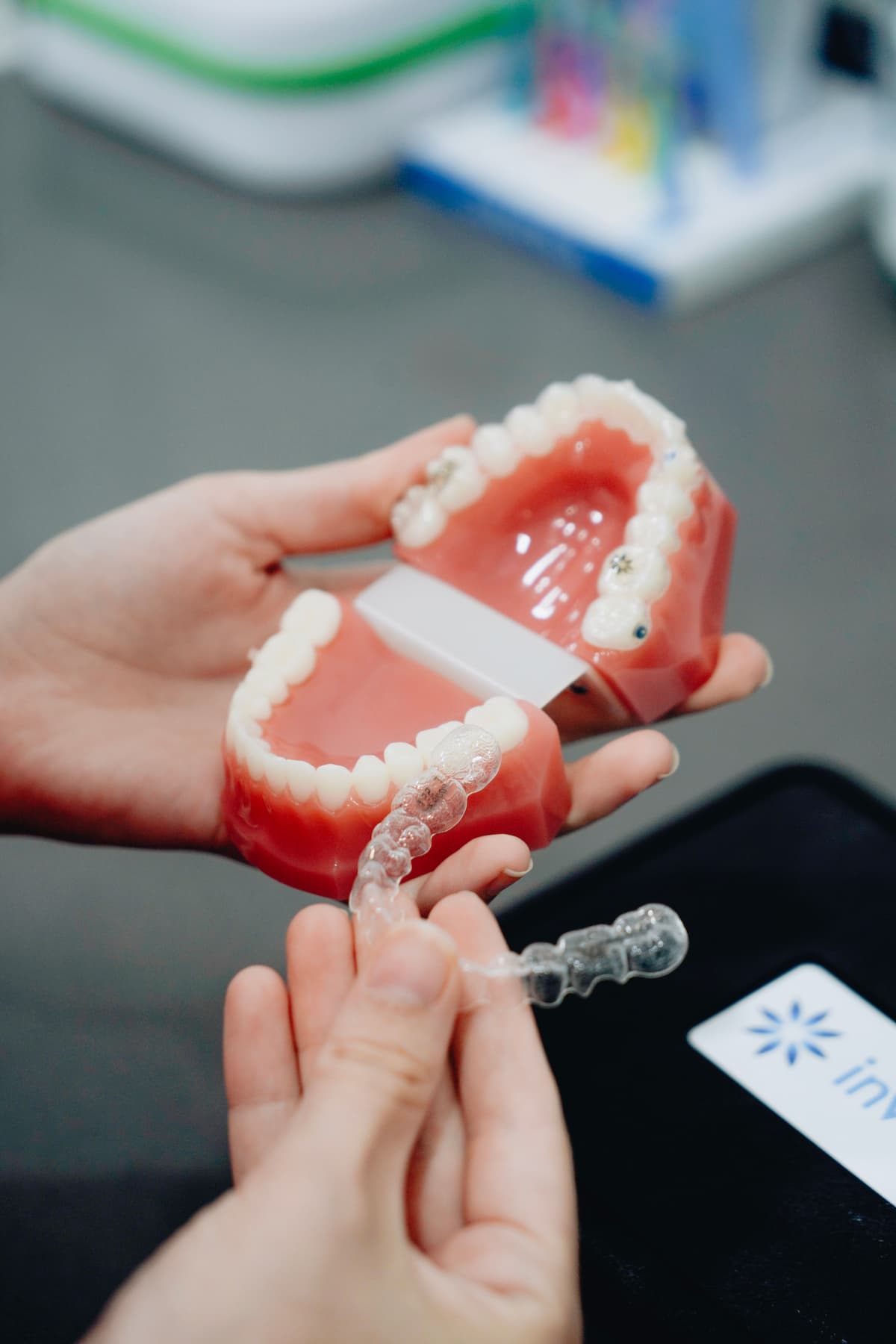 Hands holding dental models and clear aligners