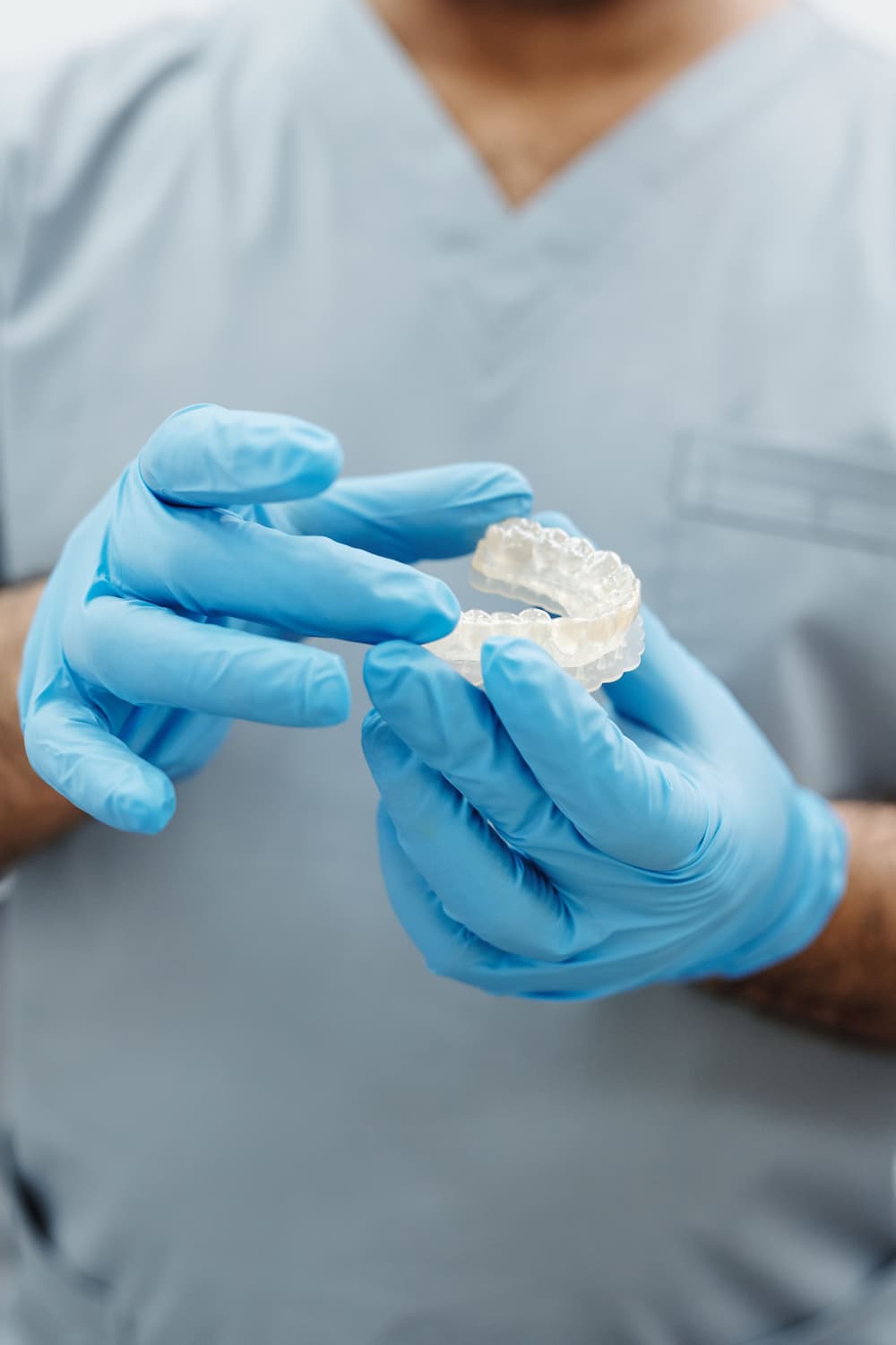Dentist holding clear dental retainer with gloved hands
