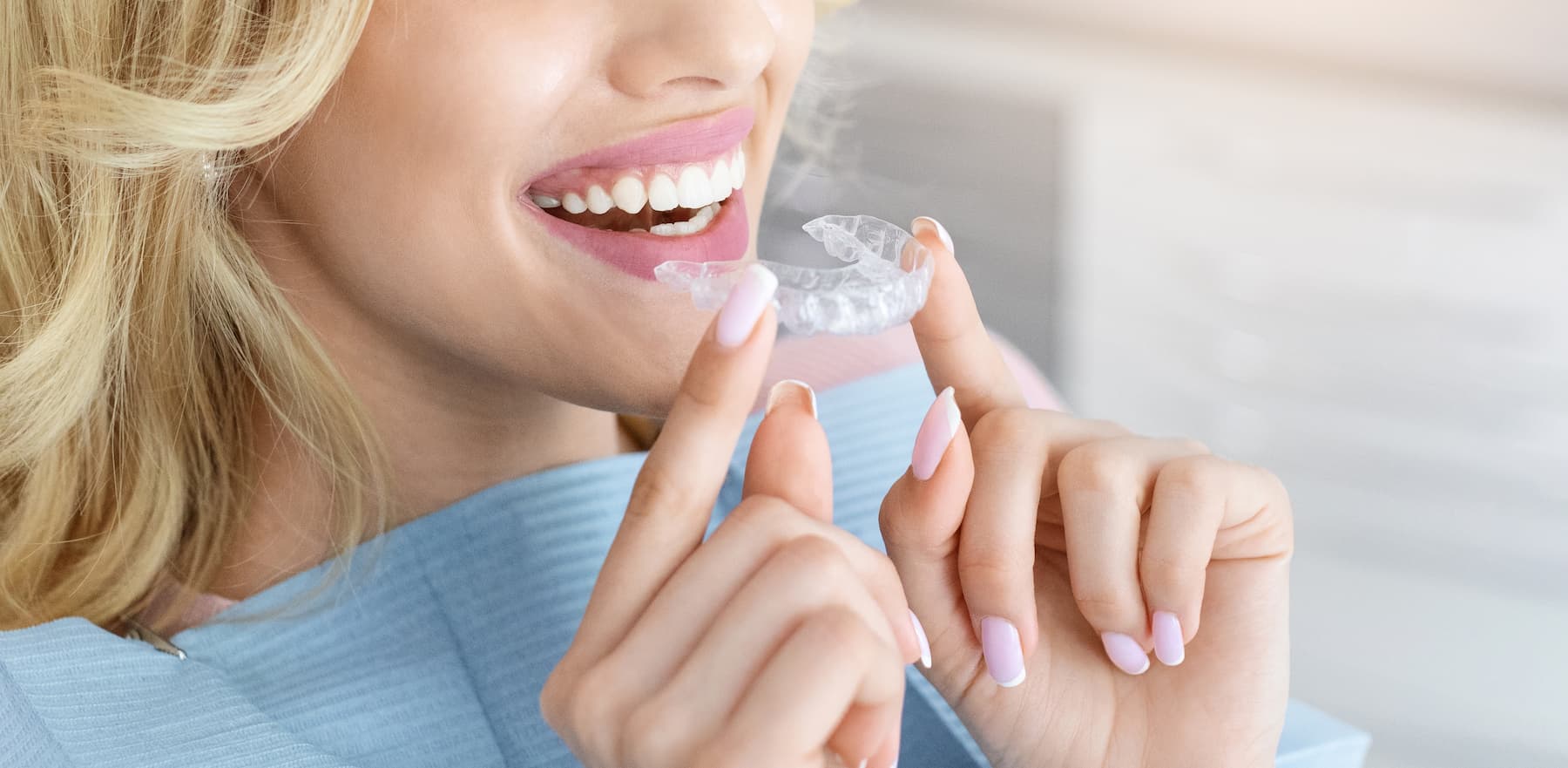 Woman holding clear dental retainer or aligner