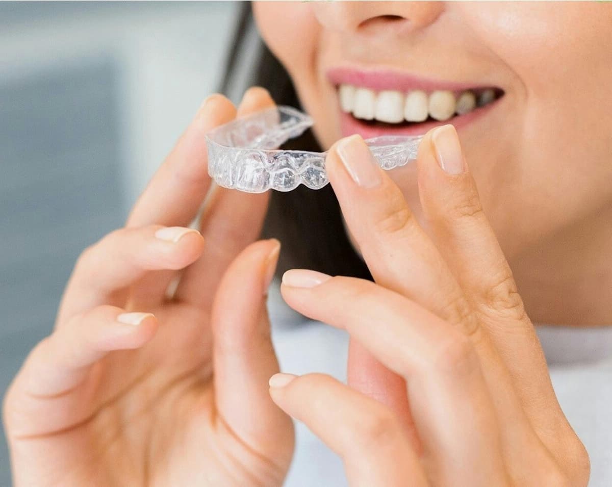 Woman inserting clear Invisalign orthodontic treatment