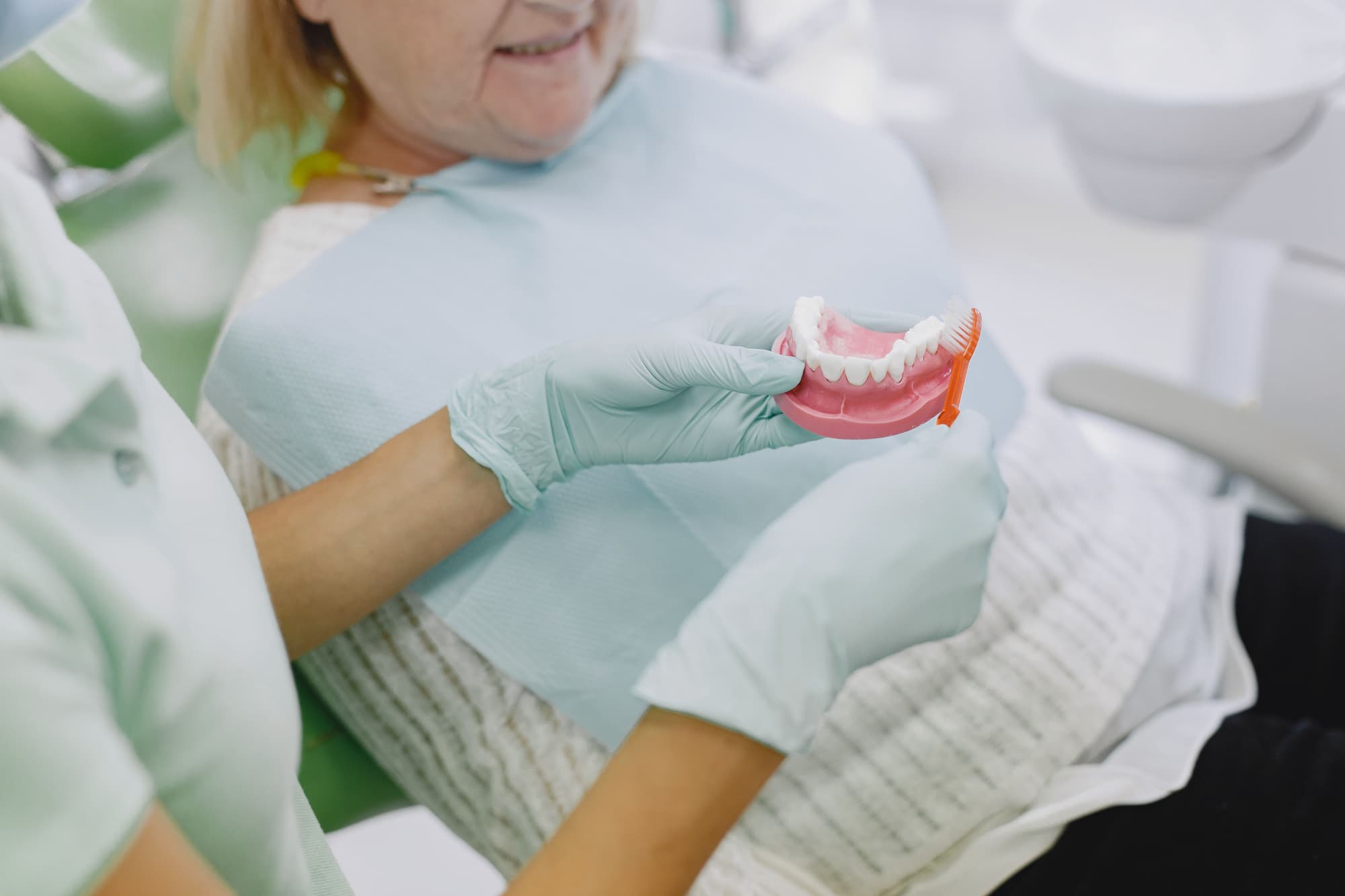 Dentist showing dental model to smiling elderly female patient