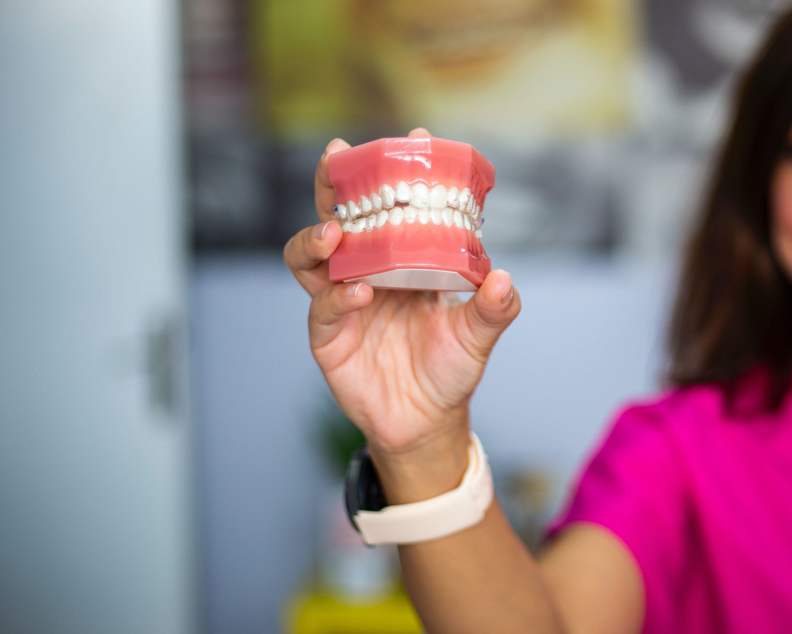 Dental professional holding a teeth model with braces
