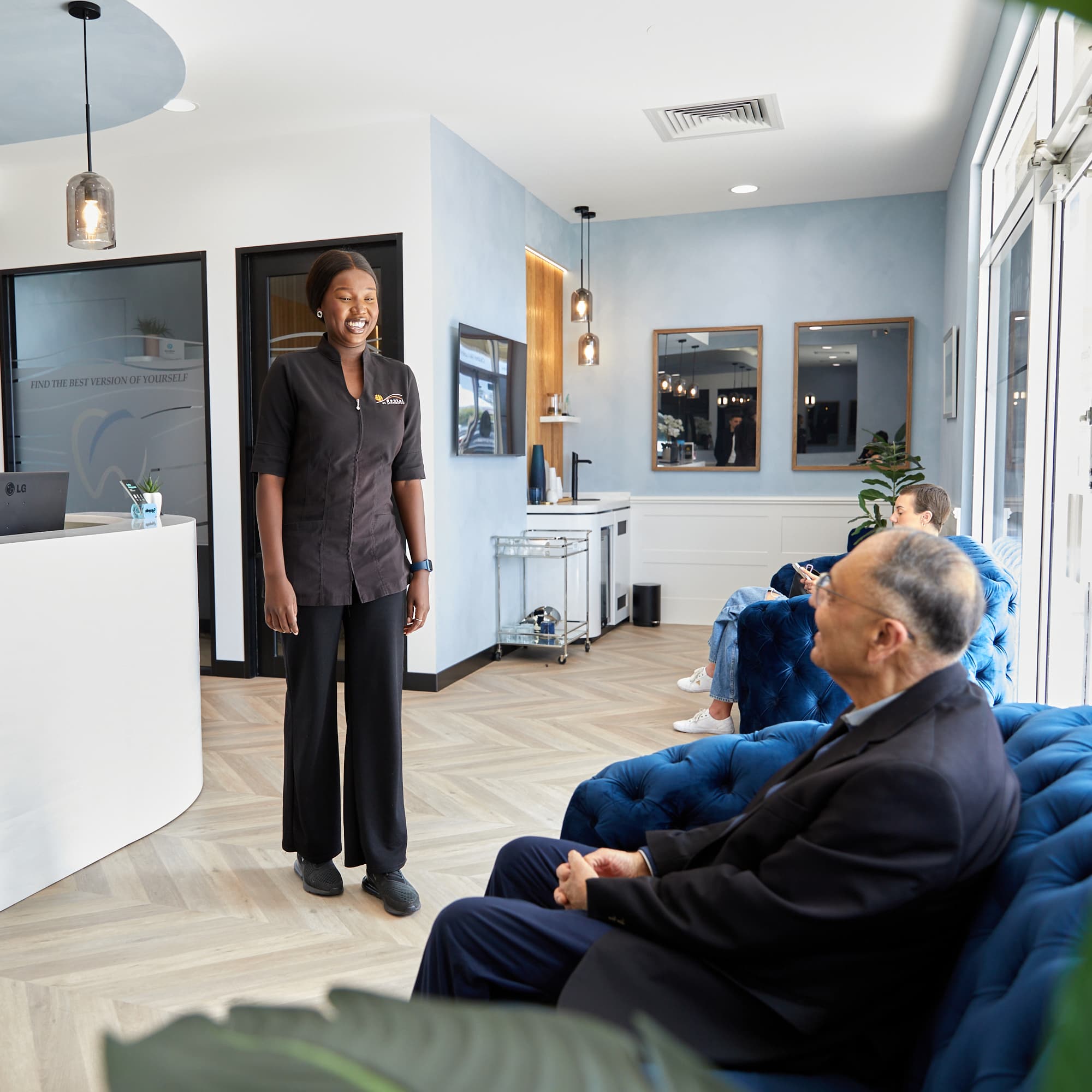 Smiling receptionist greeting patients in modern clinic waiting room